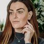 model wears enamel stacking rings and enamel huggie hoop earrings in pink, lavender and turquoise