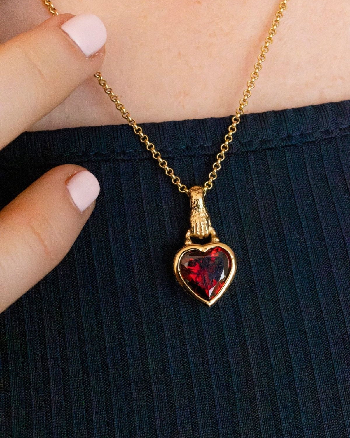 model wears garnet hand in heart gold charm necklace