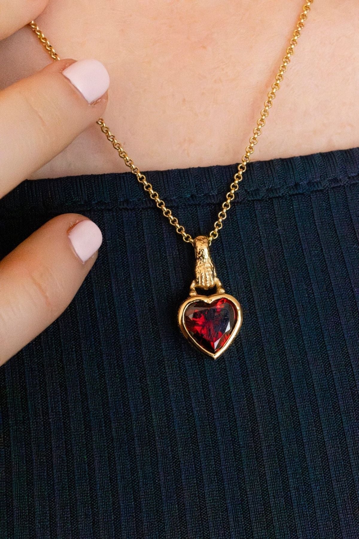model wears garnet hand in heart gold charm necklace