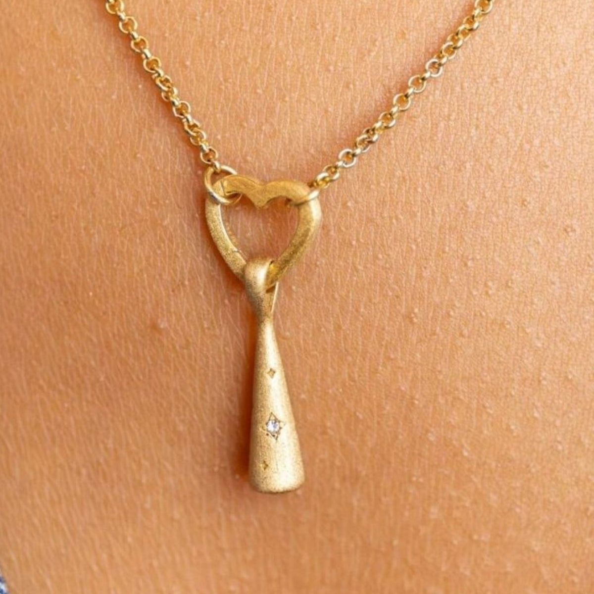 model wears Sparkly Comet Gold Charm Necklace on heart connector chain