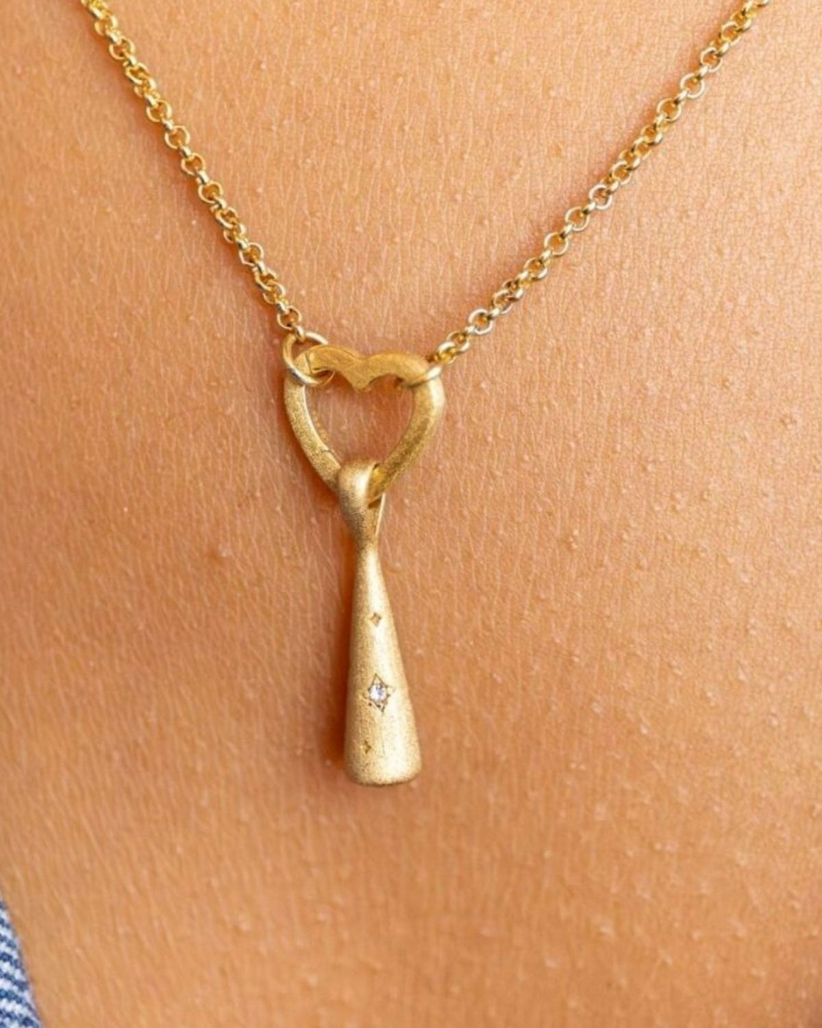 model wears Sparkly Comet Gold Charm Necklace on heart connector chain