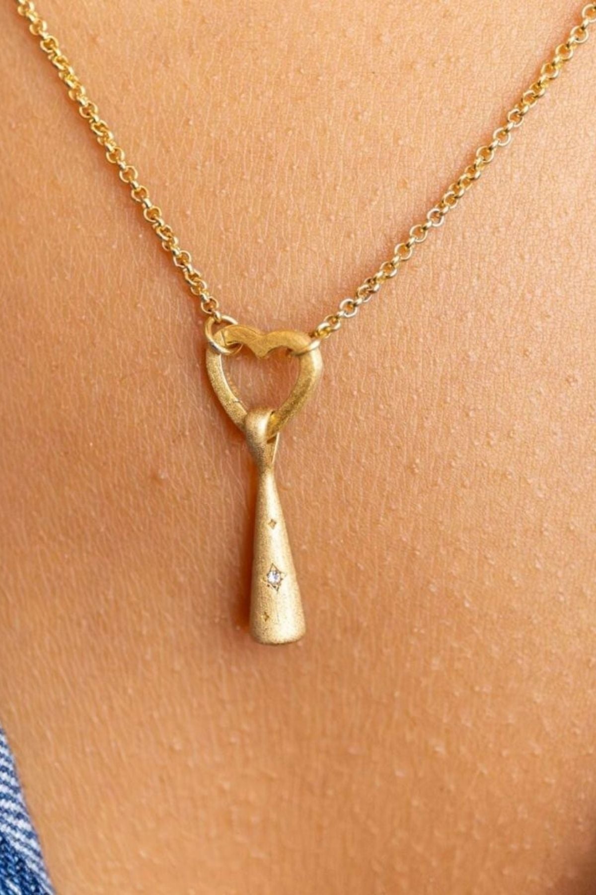 model wears Sparkly Comet Gold Charm Necklace on heart connector chain