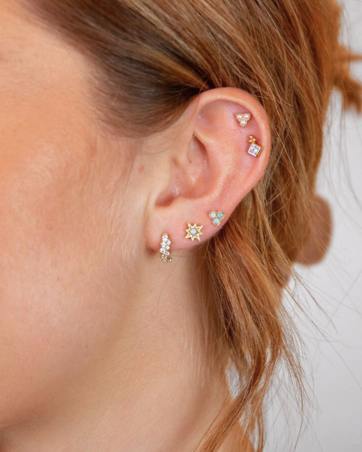 model wears triple pearl stud earrings in her helix along with other gold earrings