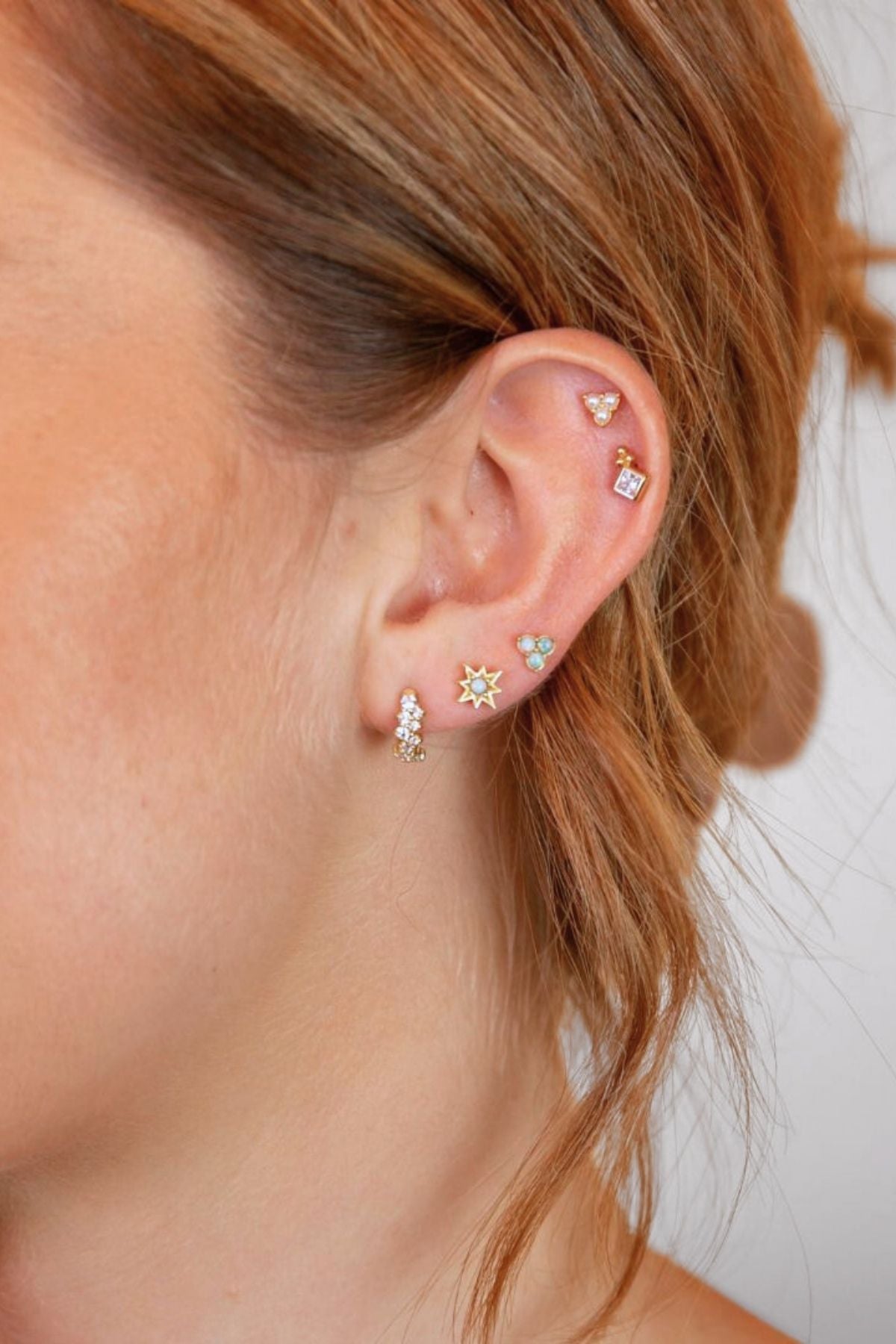 model wears triple pearl stud earrings in her helix along with other gold earrings