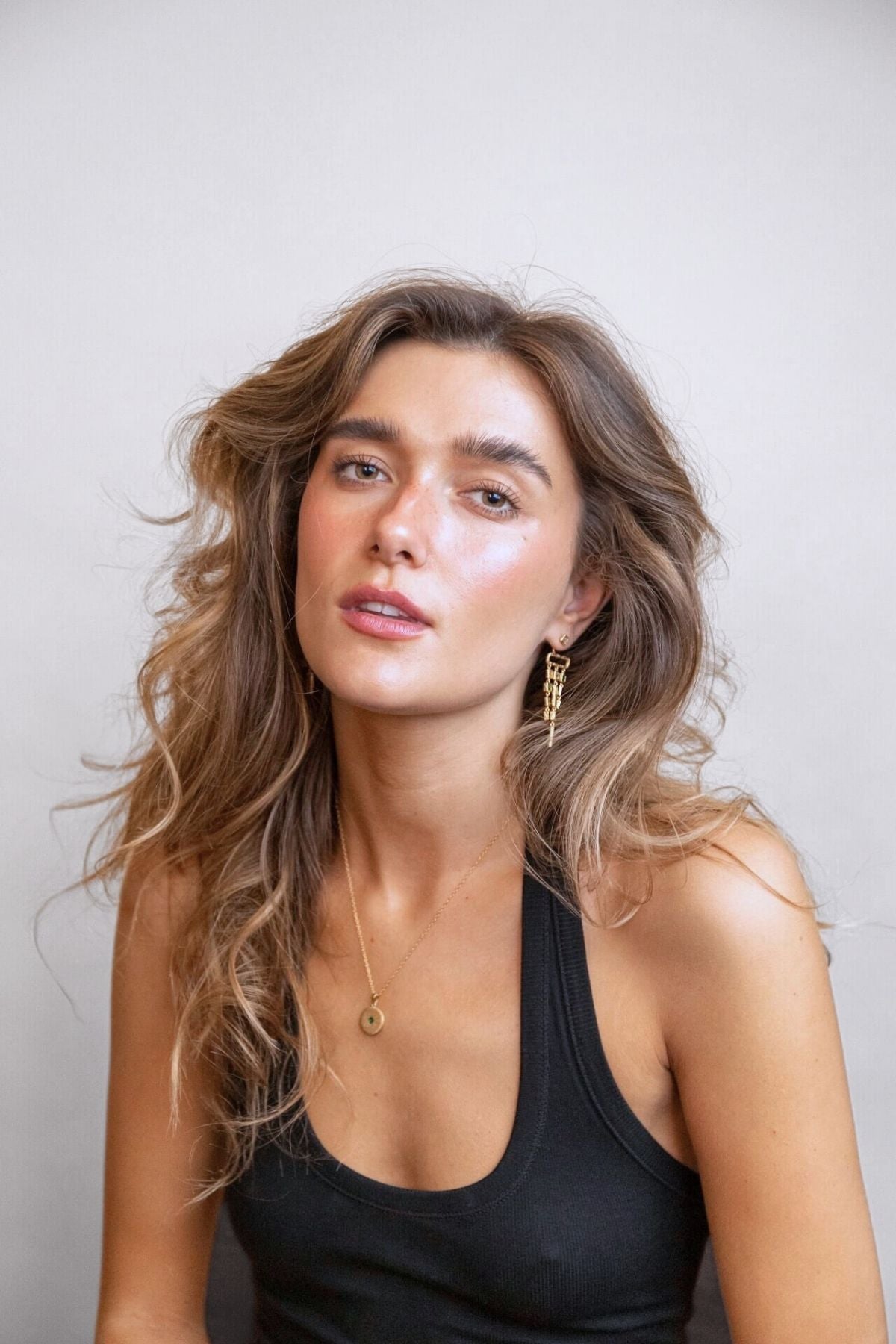 model wears emerald gold chandelier ear jacket earrings and gold lovespoon charm necklace