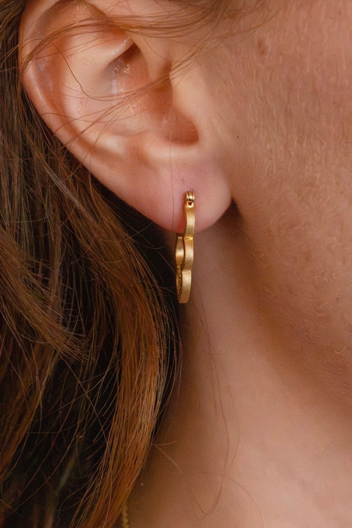 model wears gold sparkly cloud hoop earring - close up front view 