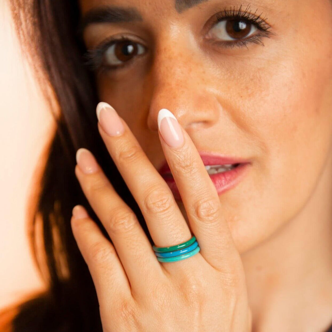 model wears enamel stacking rings in green, blue and teal
