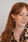 model wears sapphire gold coin drop earrings and lovespoon coin necklace
