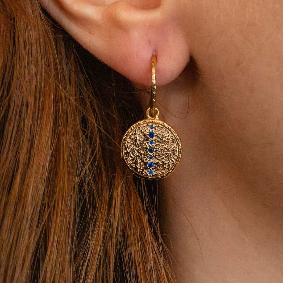 
model wears sapphire gold coin drop earrings 