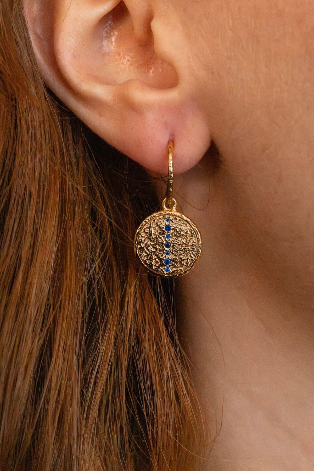 
model wears sapphire gold coin drop earrings 