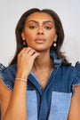 model wears sapphire gold coin drop earrings and fearless gold necklace
