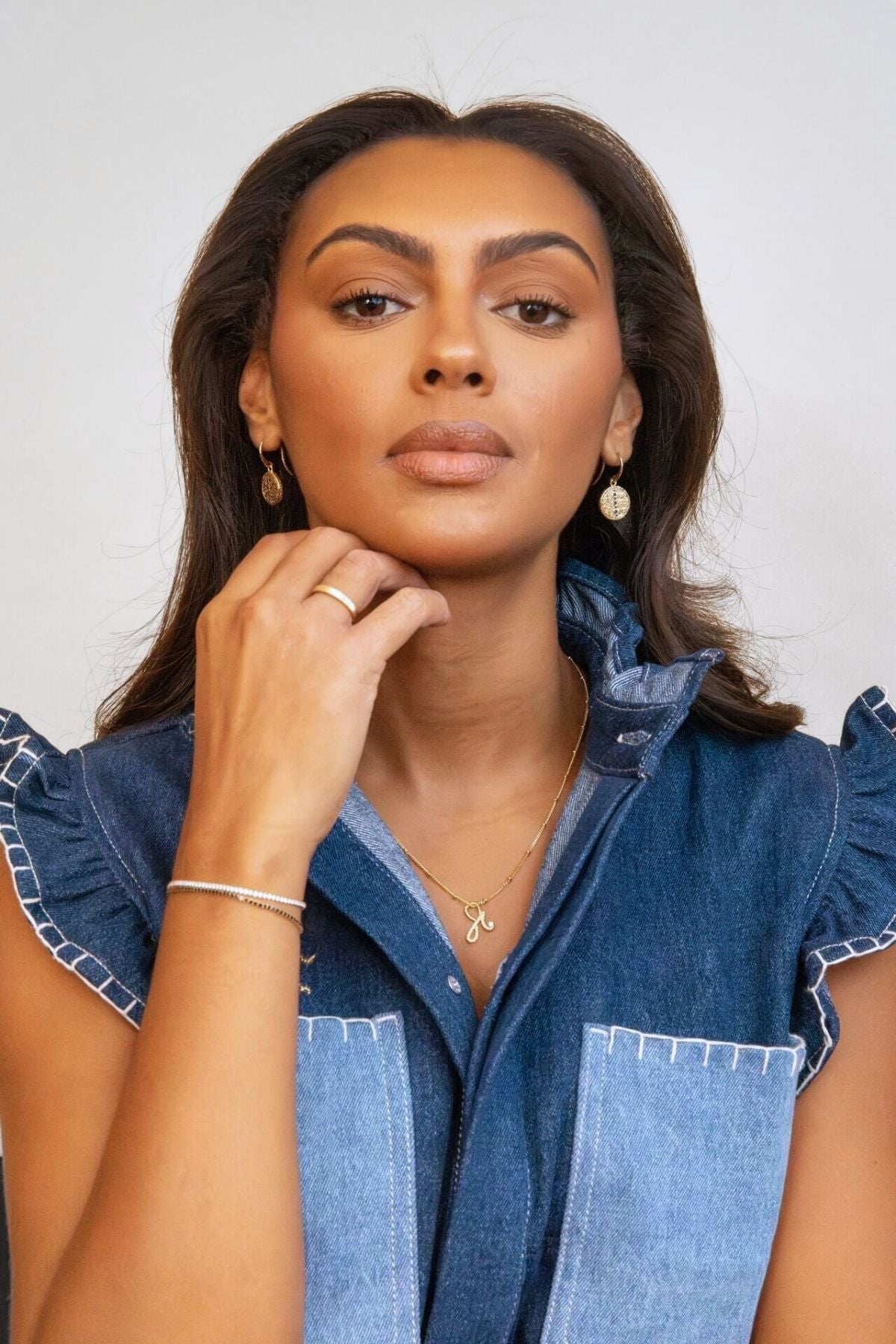 model wears sapphire gold coin drop earrings and fearless gold necklace
