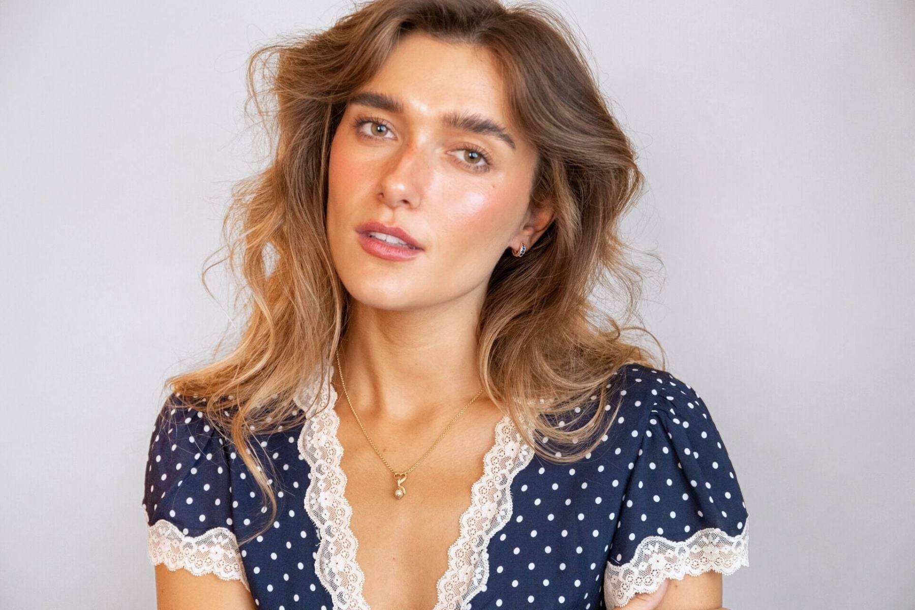 model wears sapphire huggie hoop earrings and heart charm necklace with lemon charm

