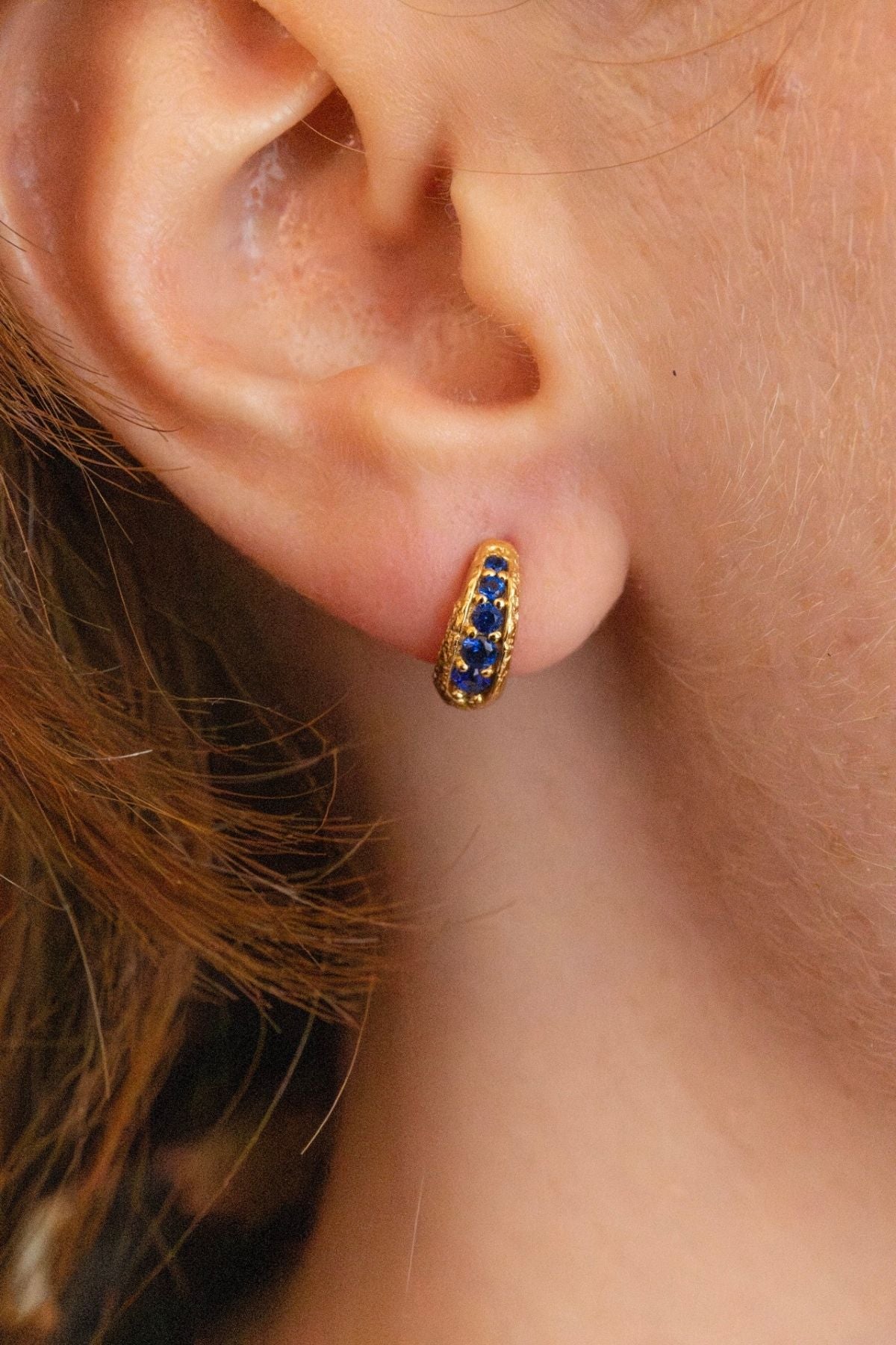 model wears sapphire huggie hoop gold earrings