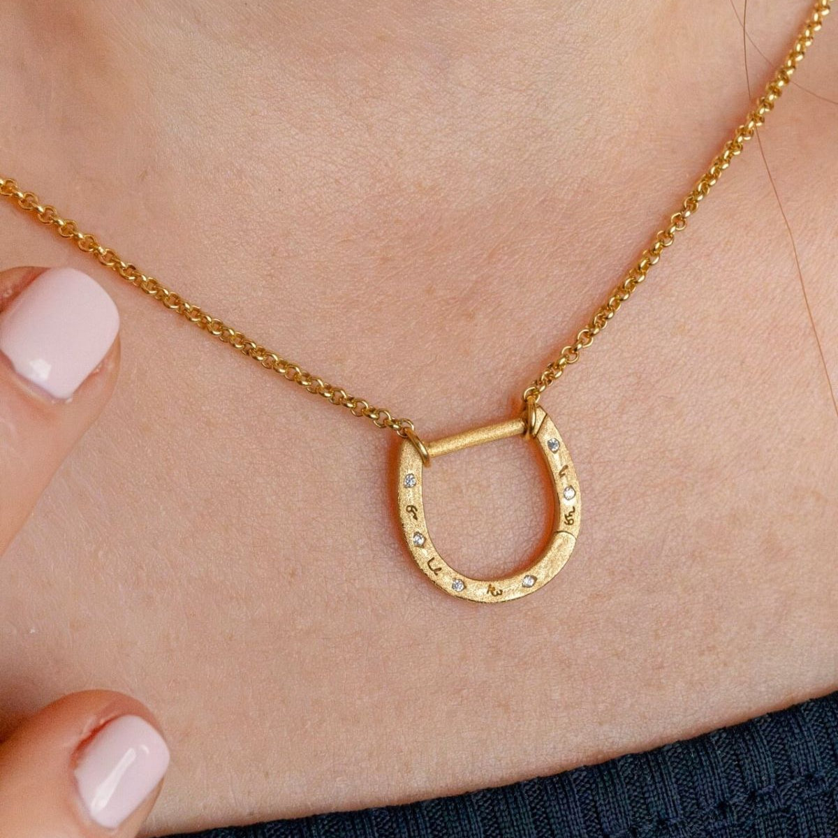 model wears shorthand gold horseshoe charm connector necklace