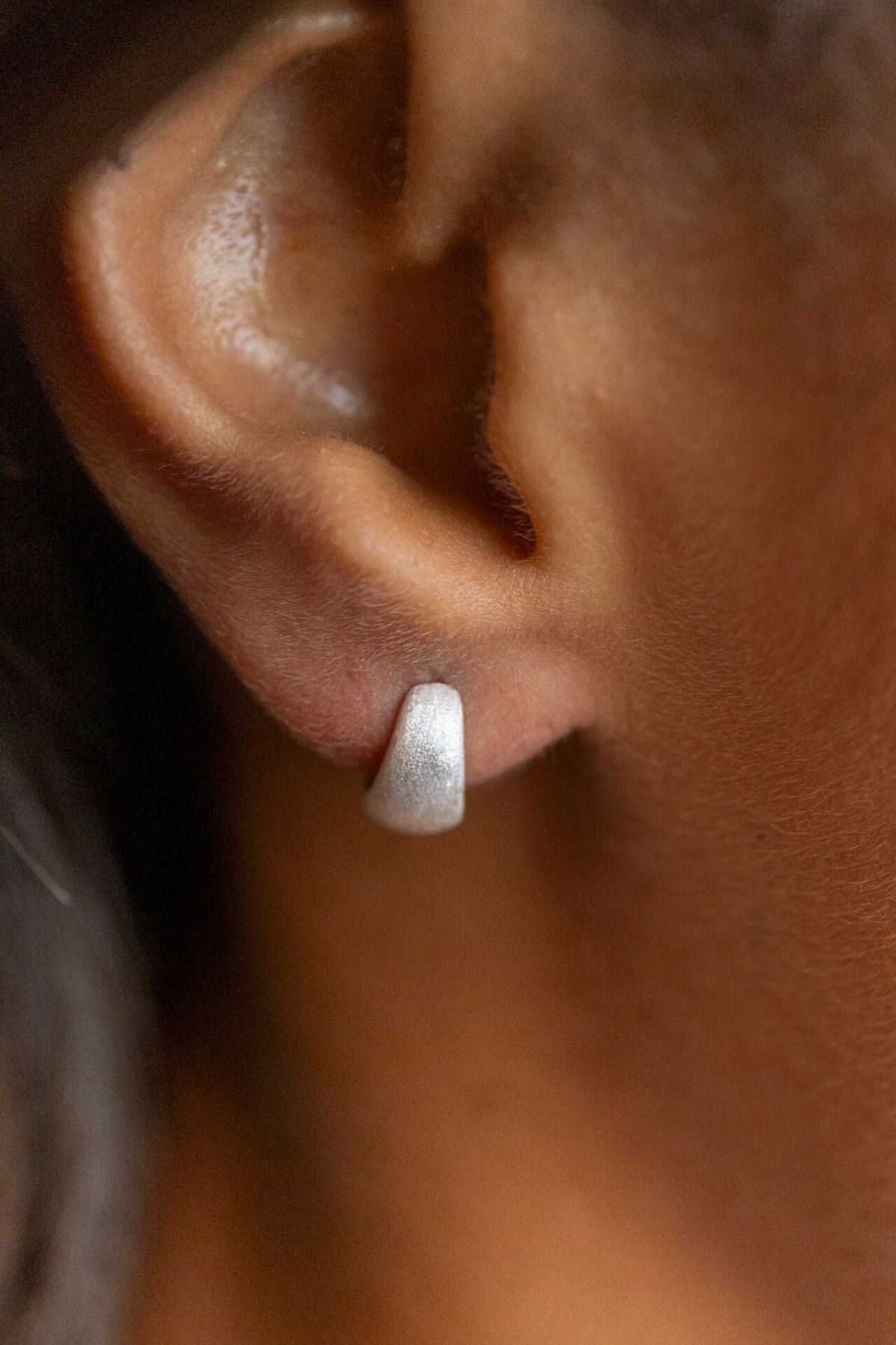 model wears Brushed Silver Chunky Huggie Hoops
