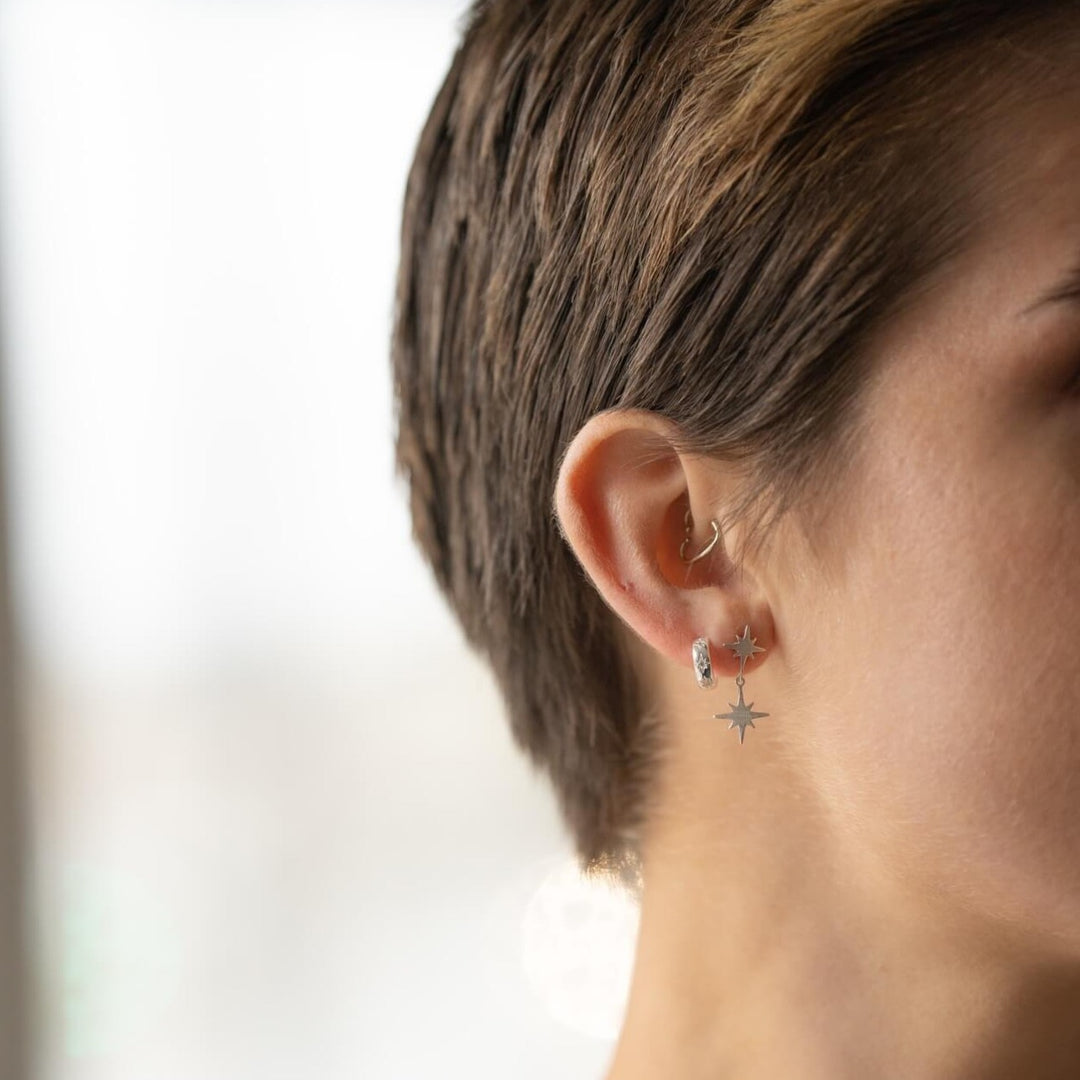 model wears silver brushed north star double stud earrings and sparky silver star huggie hoop earrings