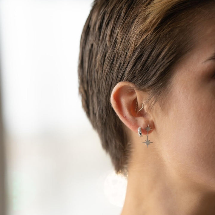 model wears silver brushed north star double stud earrings and sparky silver star huggie hoop earrings