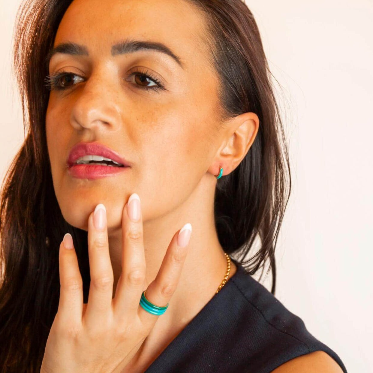 model wears Teal Enamel Huggie Hoop Earrings and enamel coloured rings