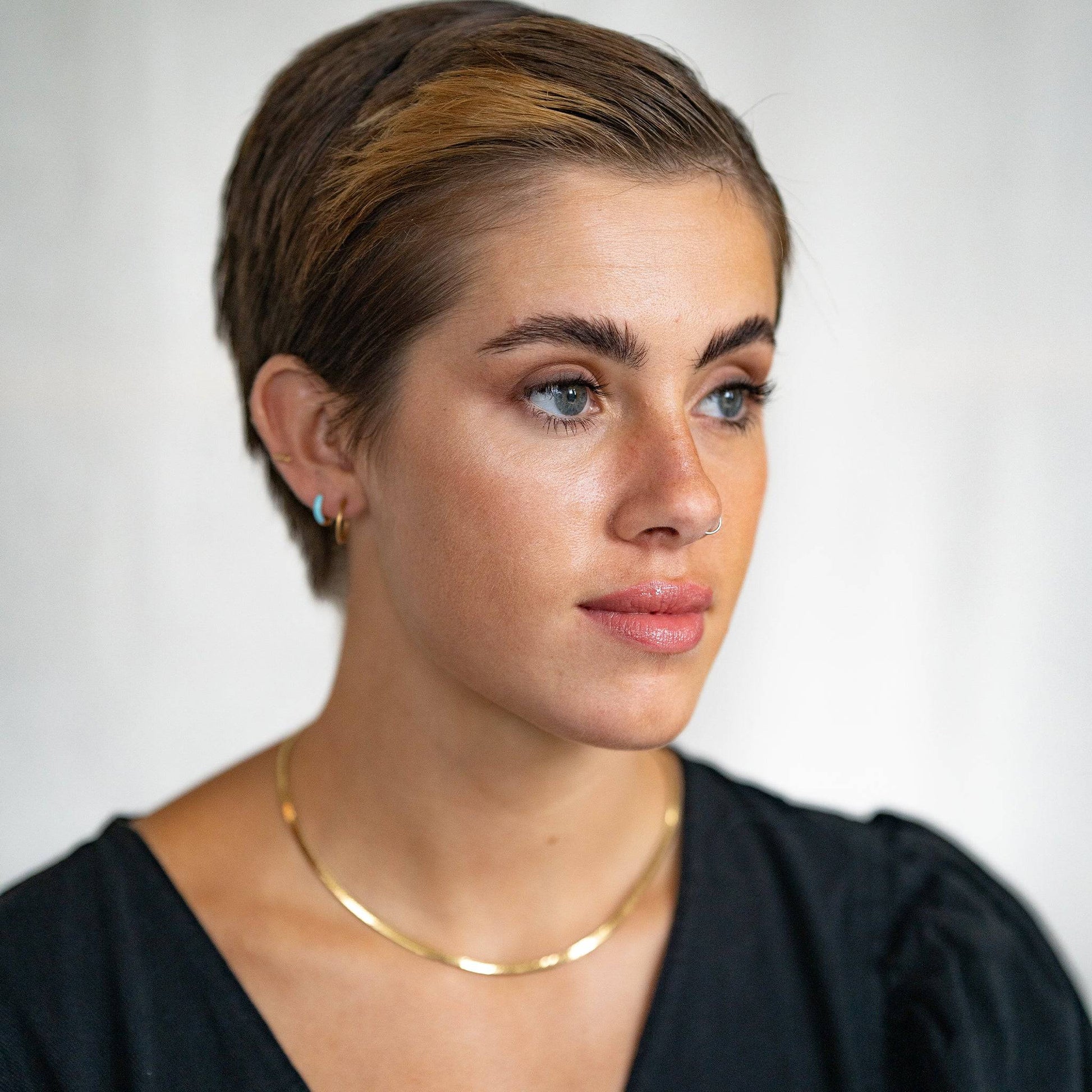 model wears Turquoise Enamel Gold Huggie Hoop Earrings and Gold Vermeil Brushed Hoop Earrings