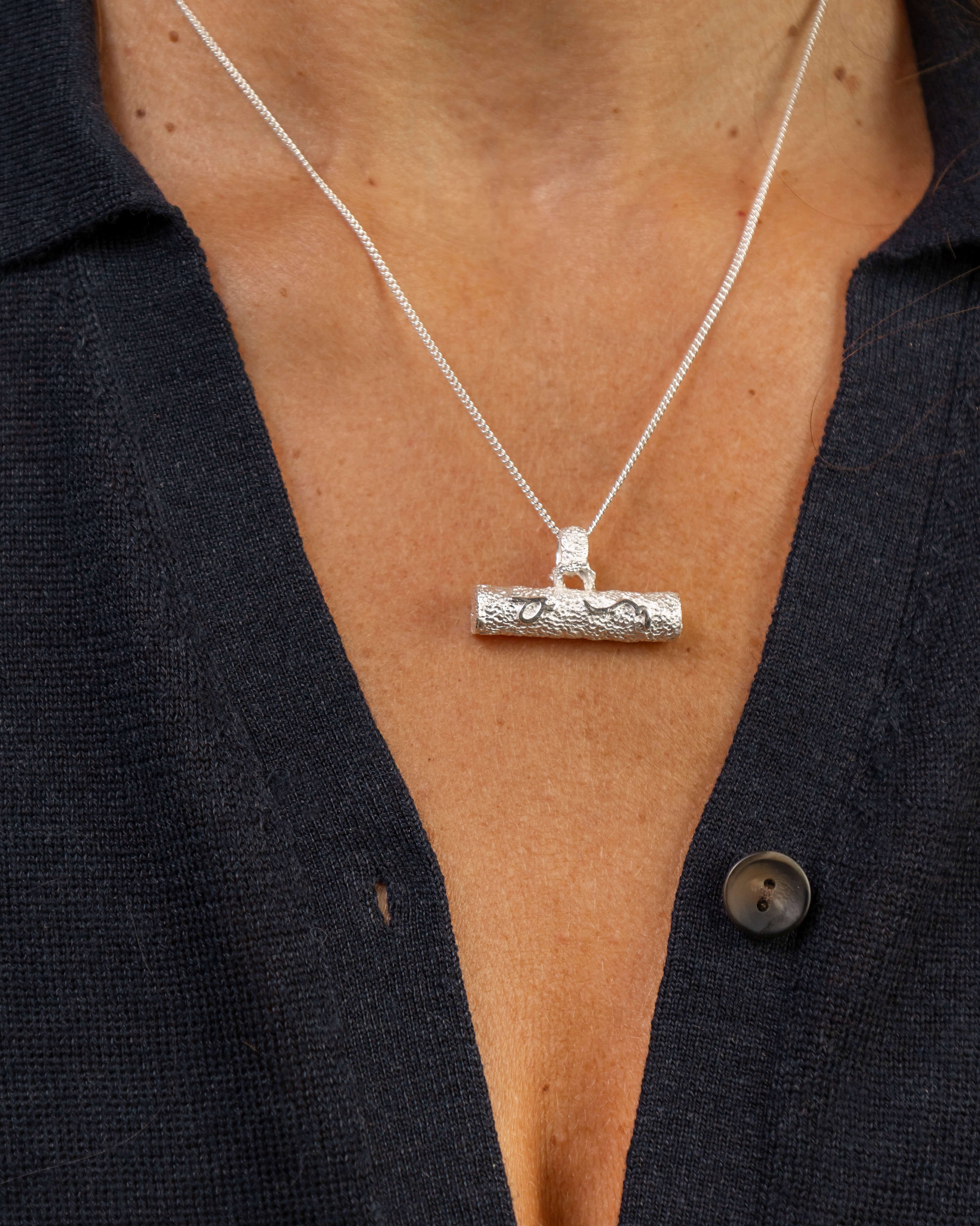 Close up of woman wearing silver T bar necklace with Difficult Woman inscribed with Teeline Shorthand 