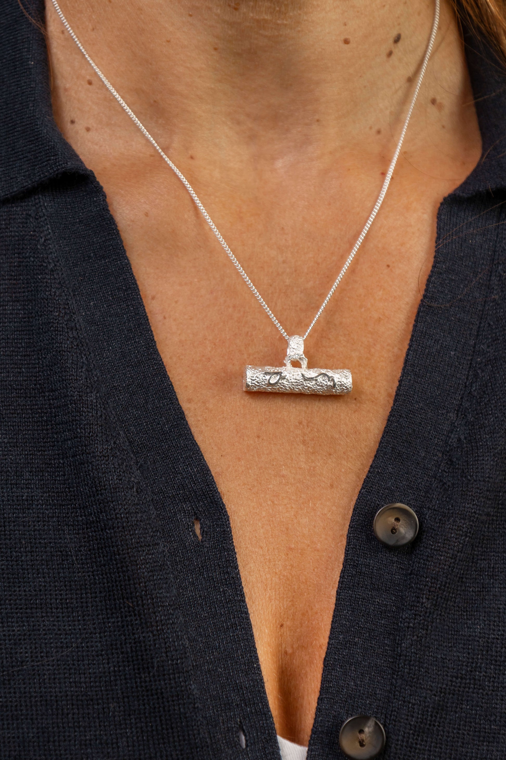Close up of woman wearing silver T bar necklace with Difficult Woman inscribed with Teeline Shorthand 