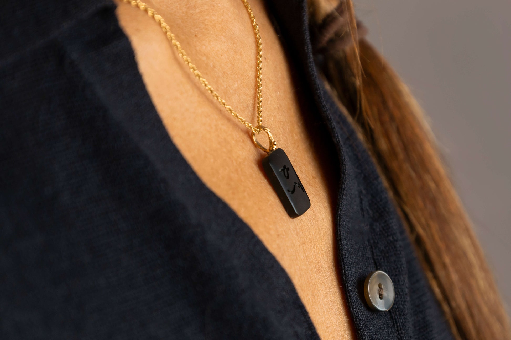Side view of woman wearing  Difficult Woman engraved in Teeline Shorthand on an Onyx Gemstone Pendant and hanging on a on twisted gold vermeil necklace  