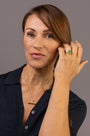 A woman wear a textured gold T bar pendant necklace with a F*** this S*** inscribed in Teeline Shorthand, paired with a dark navy button-up shirt.