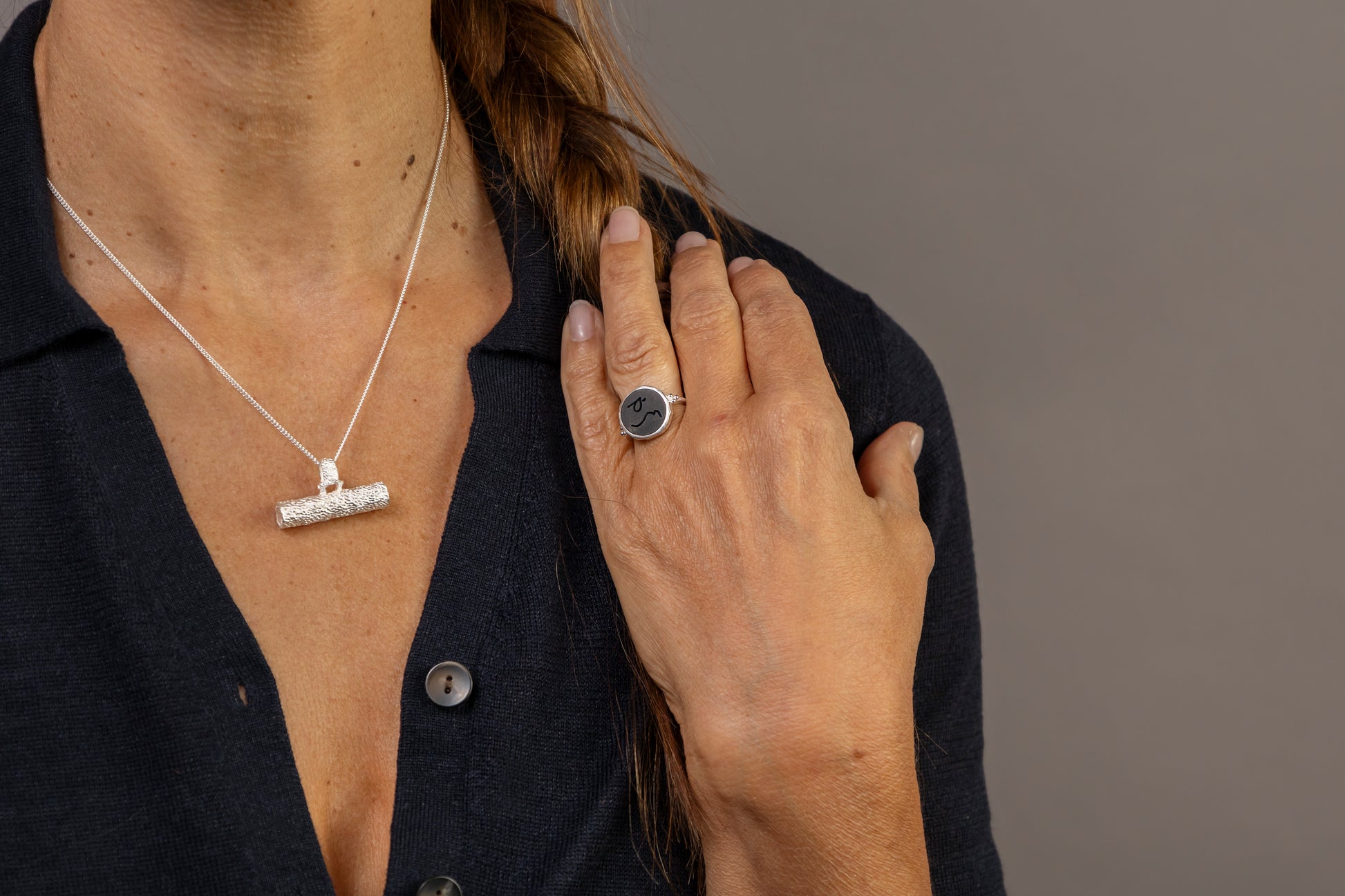 Woman wears silver textured T Bar necklace and black onyx signet ring with Difficult Woman in Teeline Shorthand inscrubed