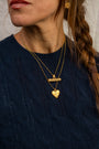 A close-up lifestyle shot of a woman wearing a gold T-bar pendant necklace with Difficult Woman and gold heart locket with Know Your Worth 